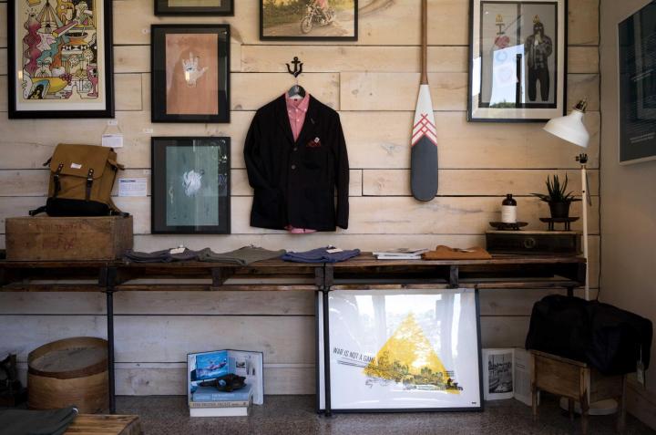 Coats, prints and a canoe paddle on the wall of a small shop