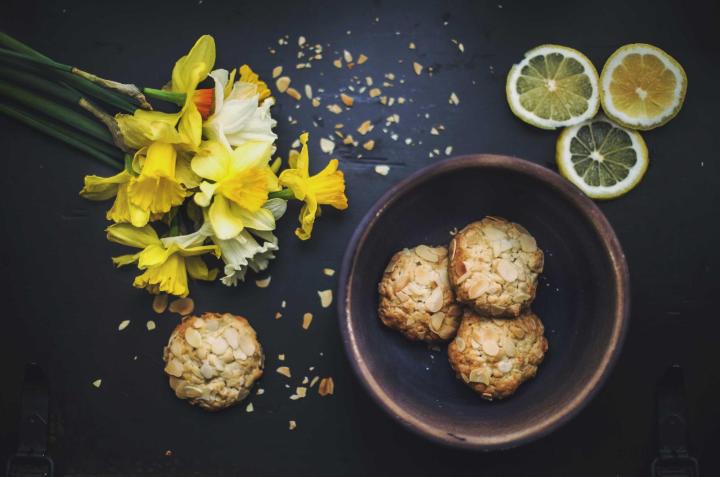 Biscuits, daffodils and lemon slices on a dark table