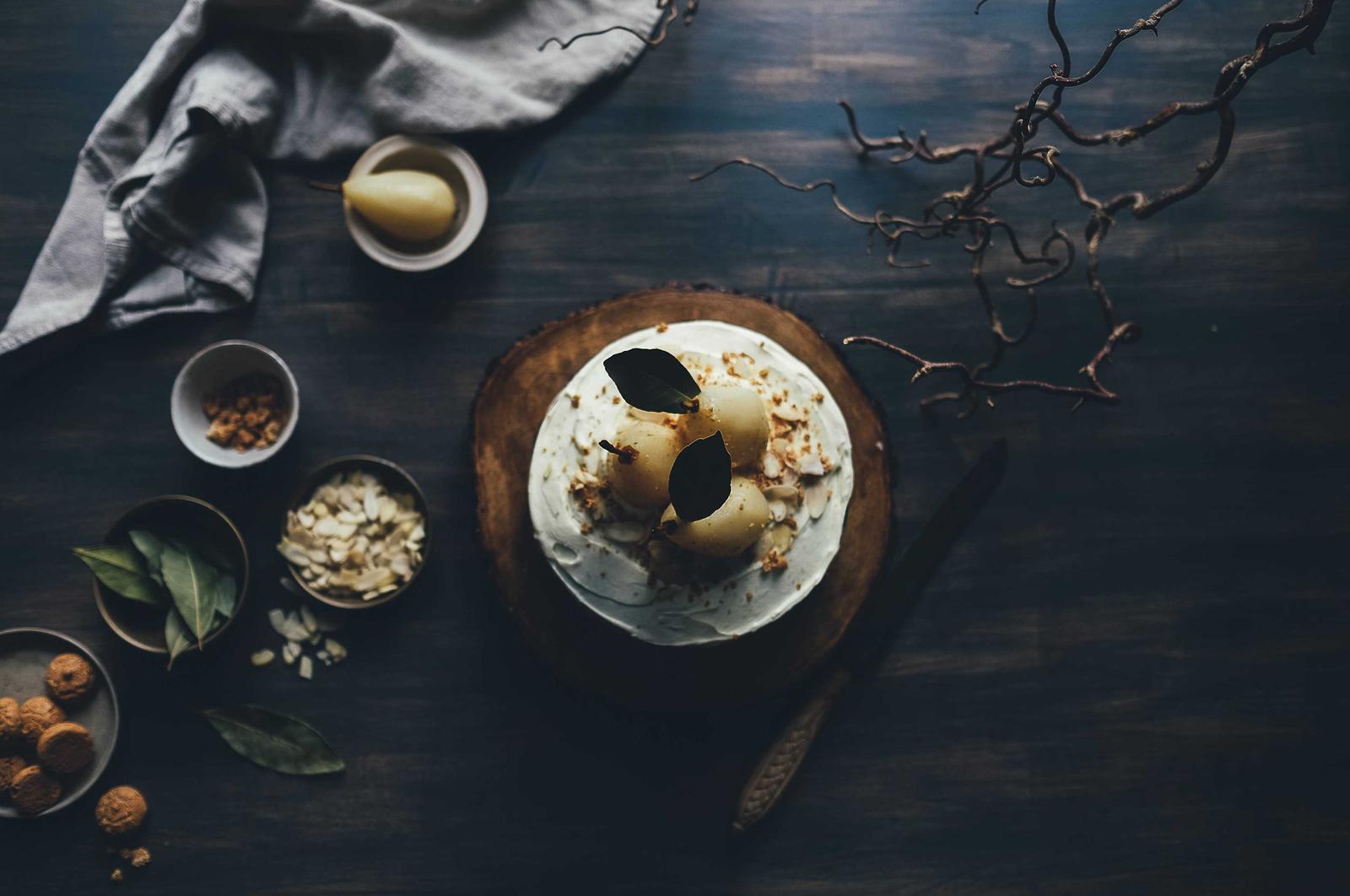 A cake among small bowls of nuts and spices on a dark table